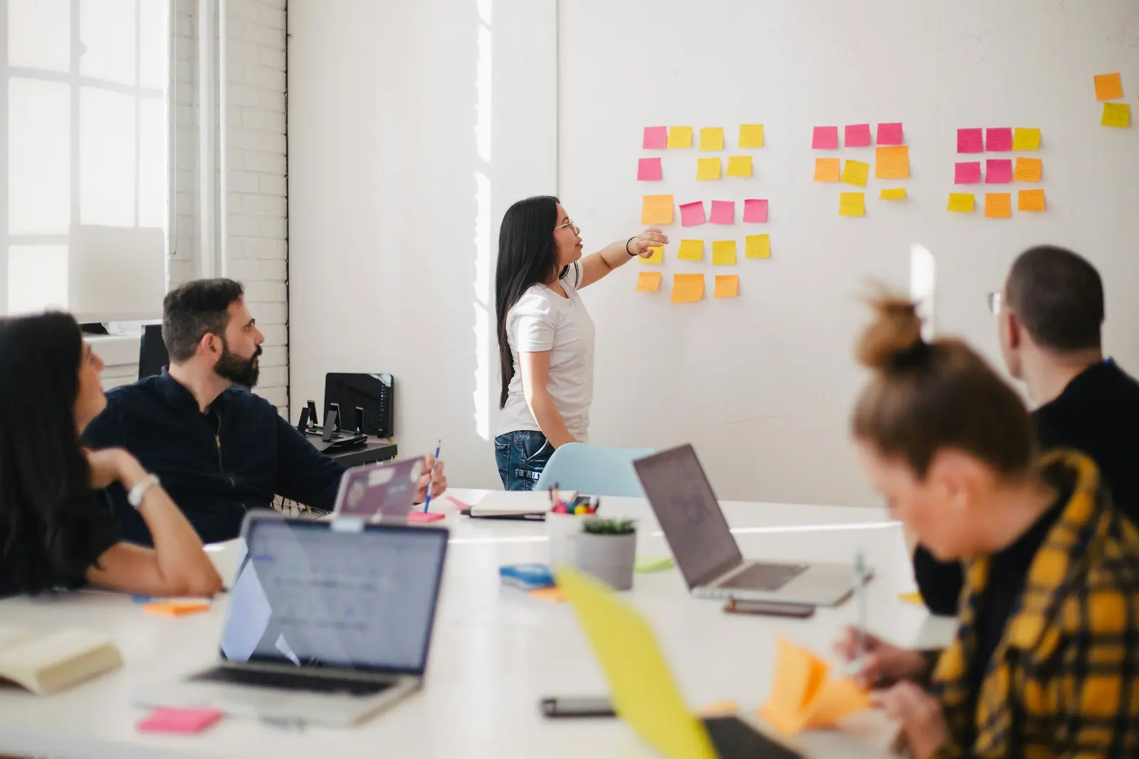 Equipo en una sesión de trabajo frente a una pizarra con notas adhesivas de colores