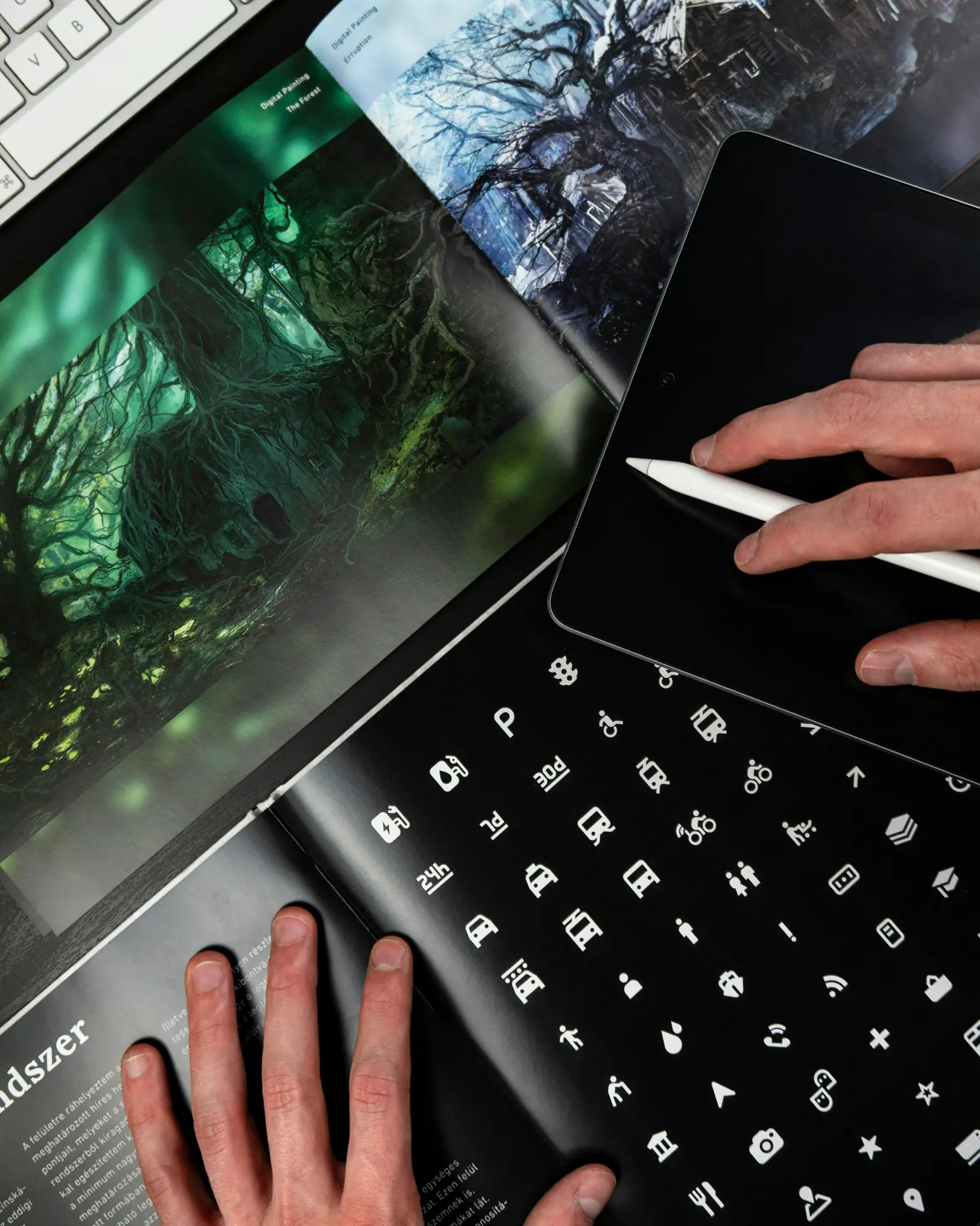Mano con un lápiz digital trabajando sobre una tableta, junto a un teclado