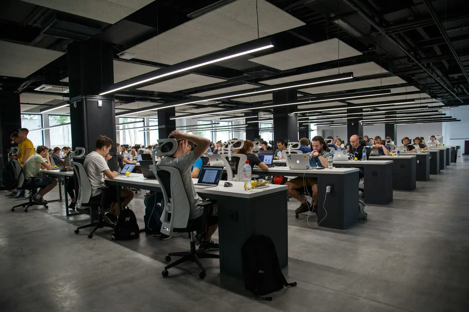 Oficina amplia de planta abierta con personas trabajando en escritorios con computadoras